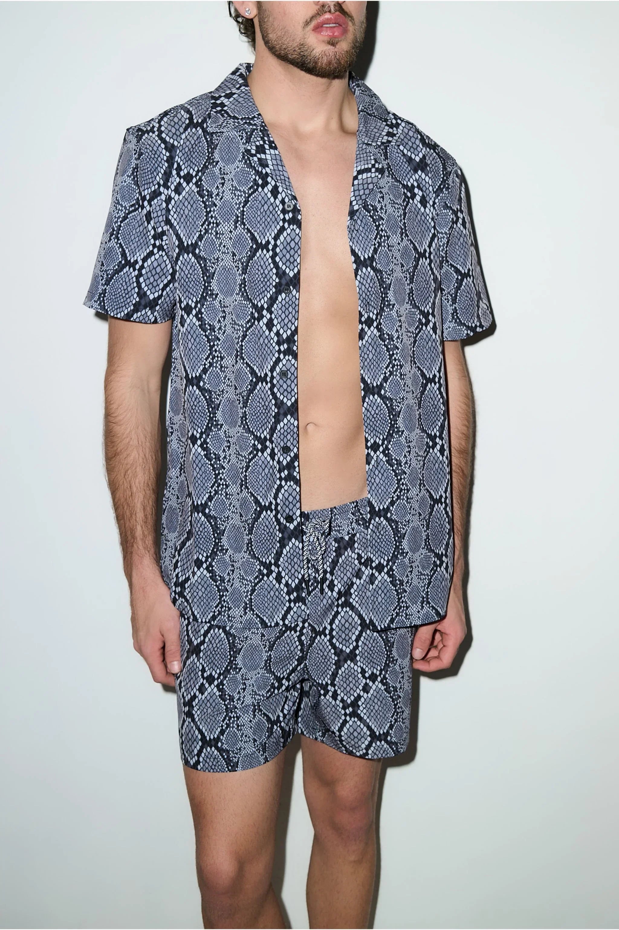 Man wearing short-sleeve shirt and shorts cabana set with blue snake print pattern