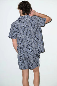 Man wearing short-sleeve cabana set with black and grey snake print, shown from the back