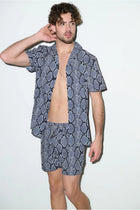 Man wearing matching short-sleeve shirt and shorts cabana set with snake print