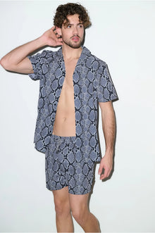 Man wearing matching short-sleeve shirt and shorts cabana set with snake print